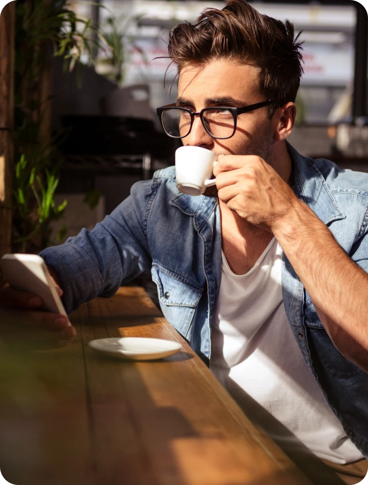 Break Coffee Franchise 1 A person sips on a cup of espresso while looking at their phone at an outdoor coffee shop.
